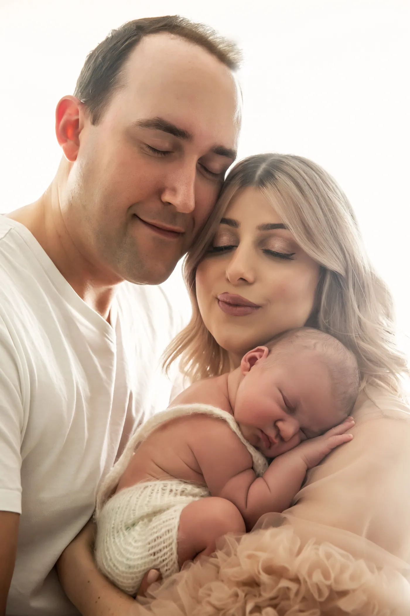 Familie mit Neugeborenem, warme, cremefarbene Aufnahme.